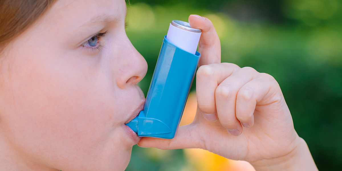 Kid taking a puff from an inhaler.
