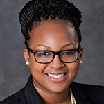 Photo of Assistant Director of Student Affairs Krystal Jones in a suit smiling brightly at camera.