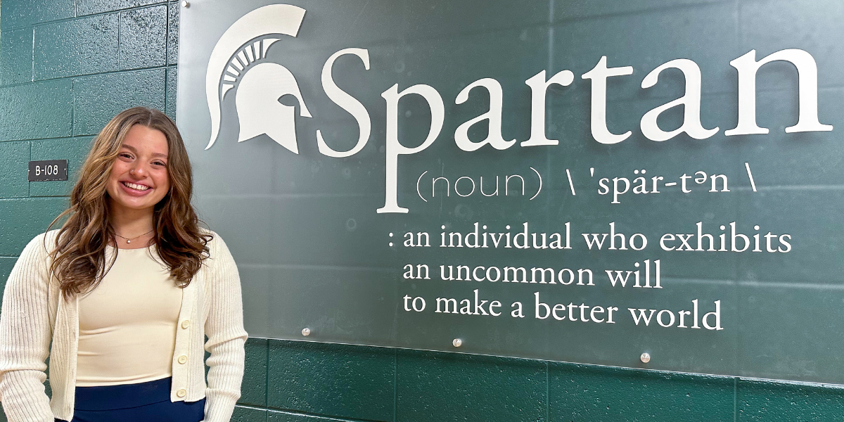 A person is smiling while standing in front of a wall that displays the definition of 