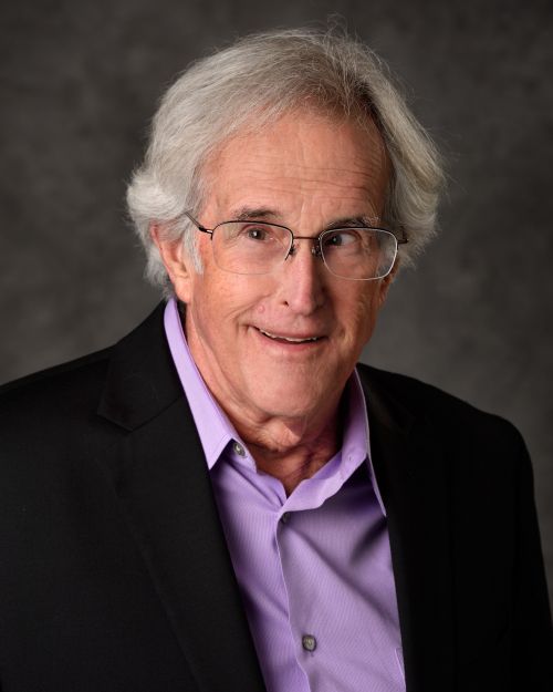 white man with grey hair and glasses smiling