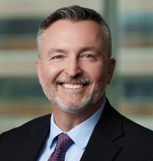 A headshot of Anthonie Burke smiling in front of a blurred background.