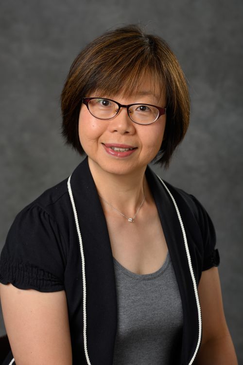 Photo of Horng Shiuann Wu with straight dark hair and dark eyes smiling at camera on portrait backdrop